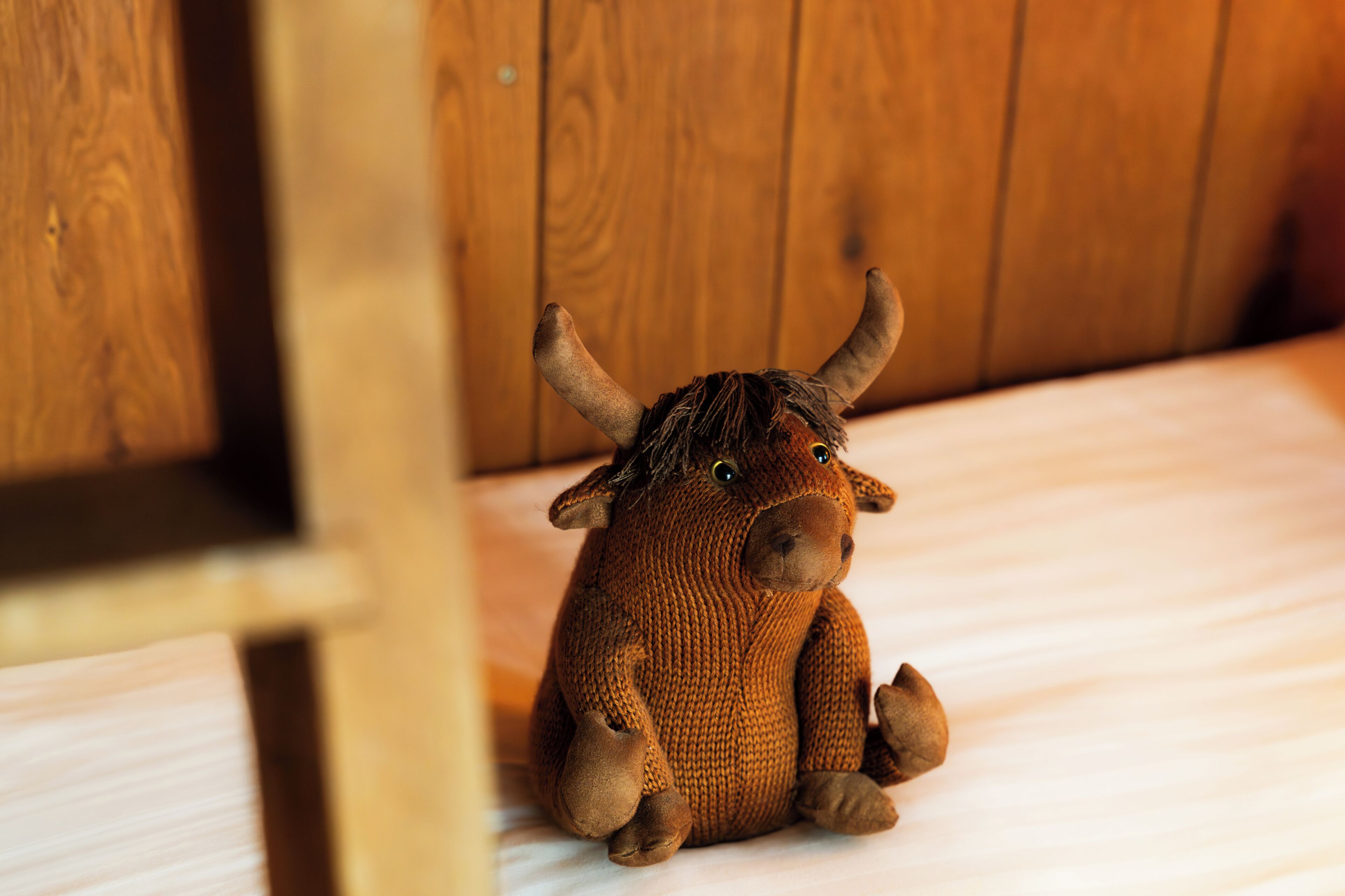 A brown stuffed animal with horns sitting on a wooden surface.