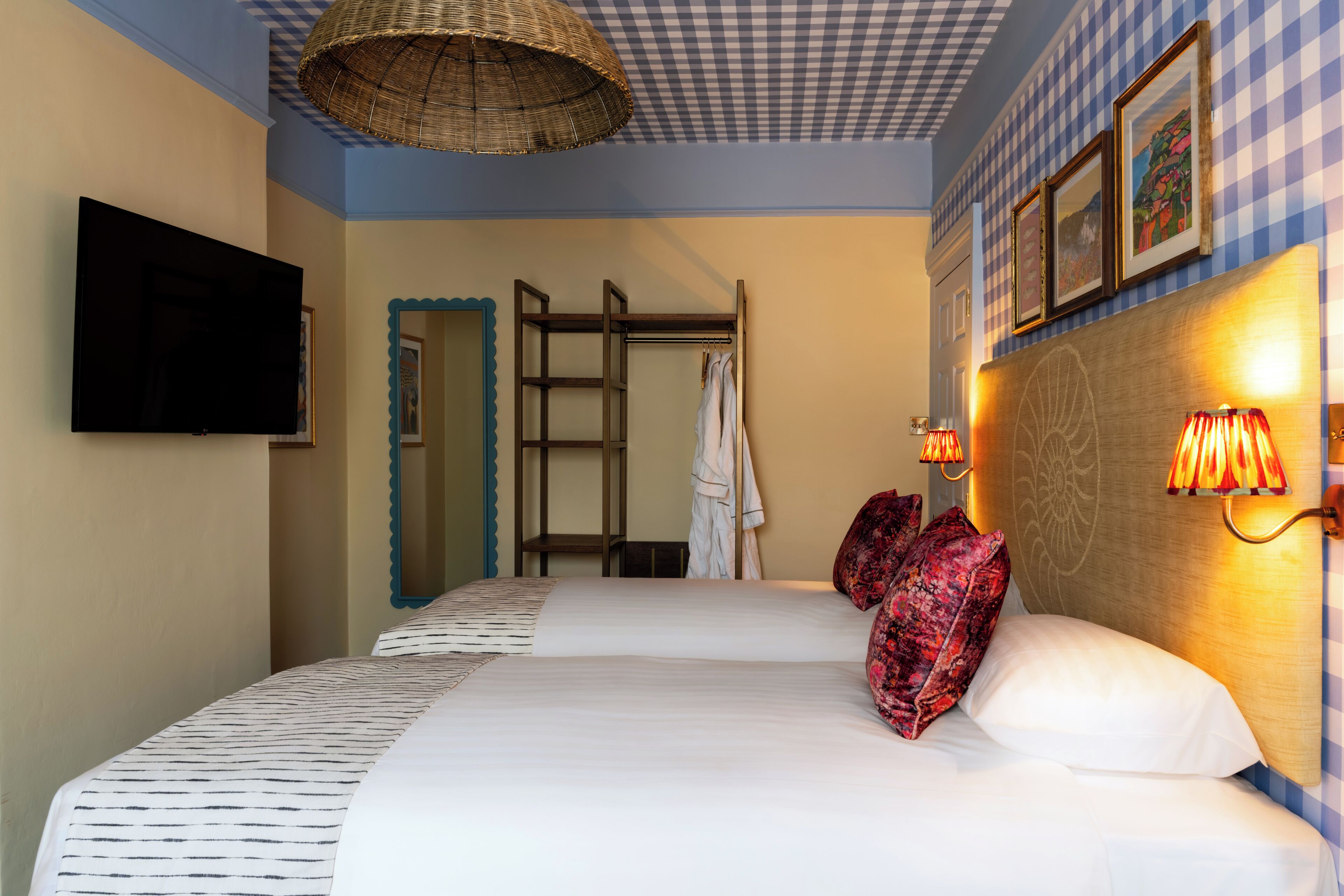 Ein Hotelzimmer mit einem Bett, einem Fernseher, einem Kleiderschrank, einem Spiegel und einer Wand mit Rautenmuster.