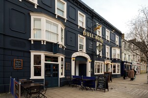 A building with a sign reading 'BULL HOTEL' and a corner seating area with tables and chairs.