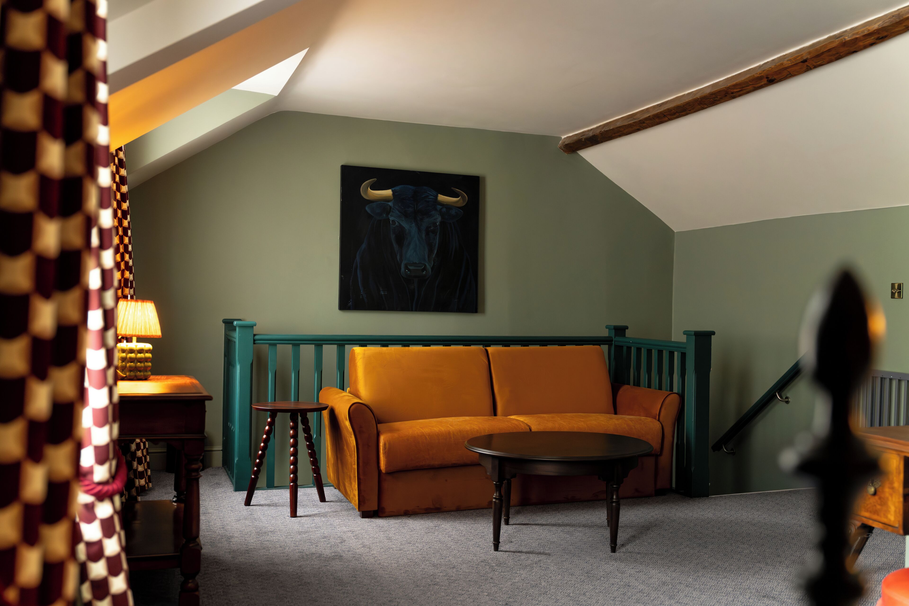 A room with a sofa, a table, a lamp, and a painting of a bull.
