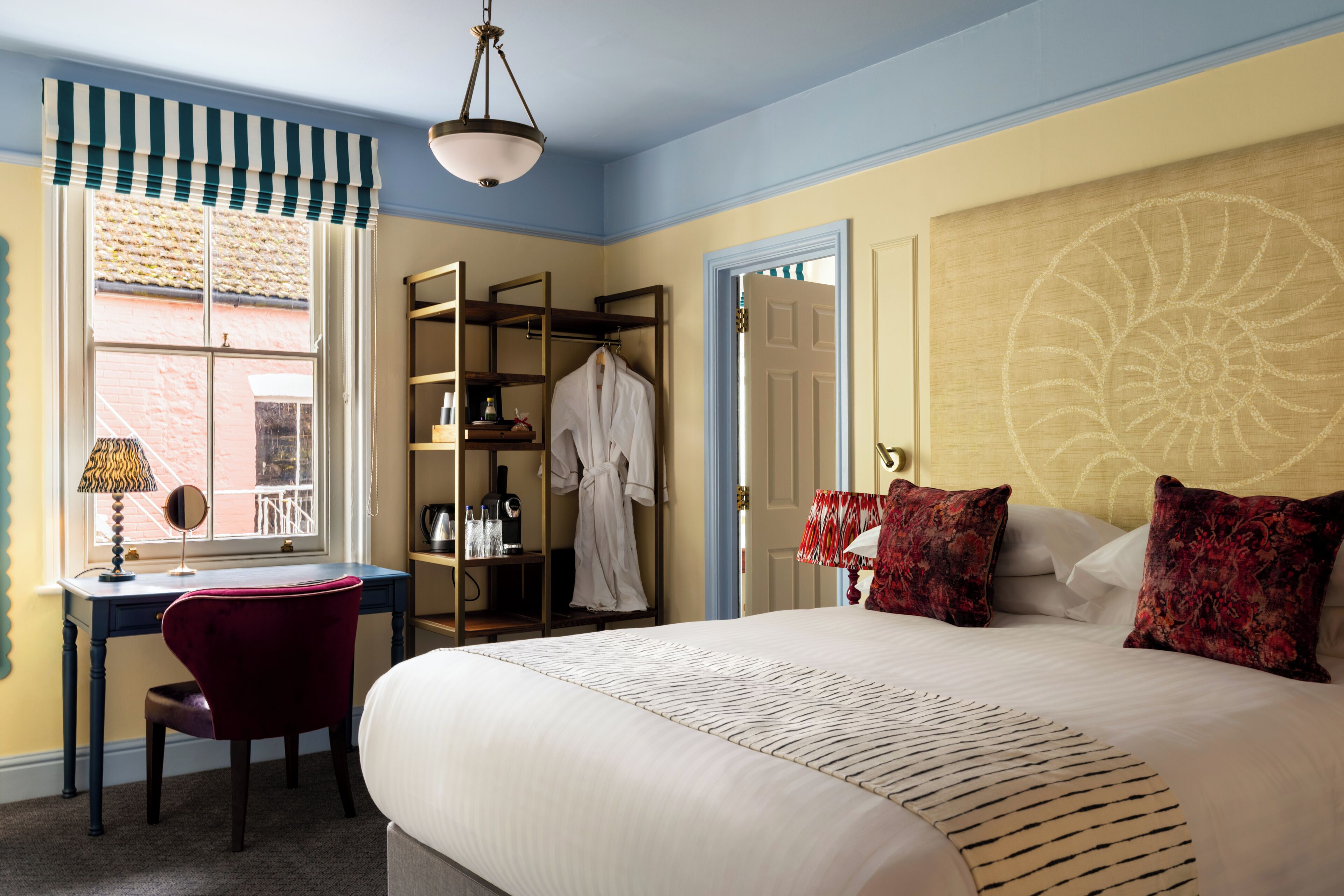 Une chambre d’hôtel avec un lit, un bureau et une chaise, une armoire et une fenêtre donnant sur un beau paysage.