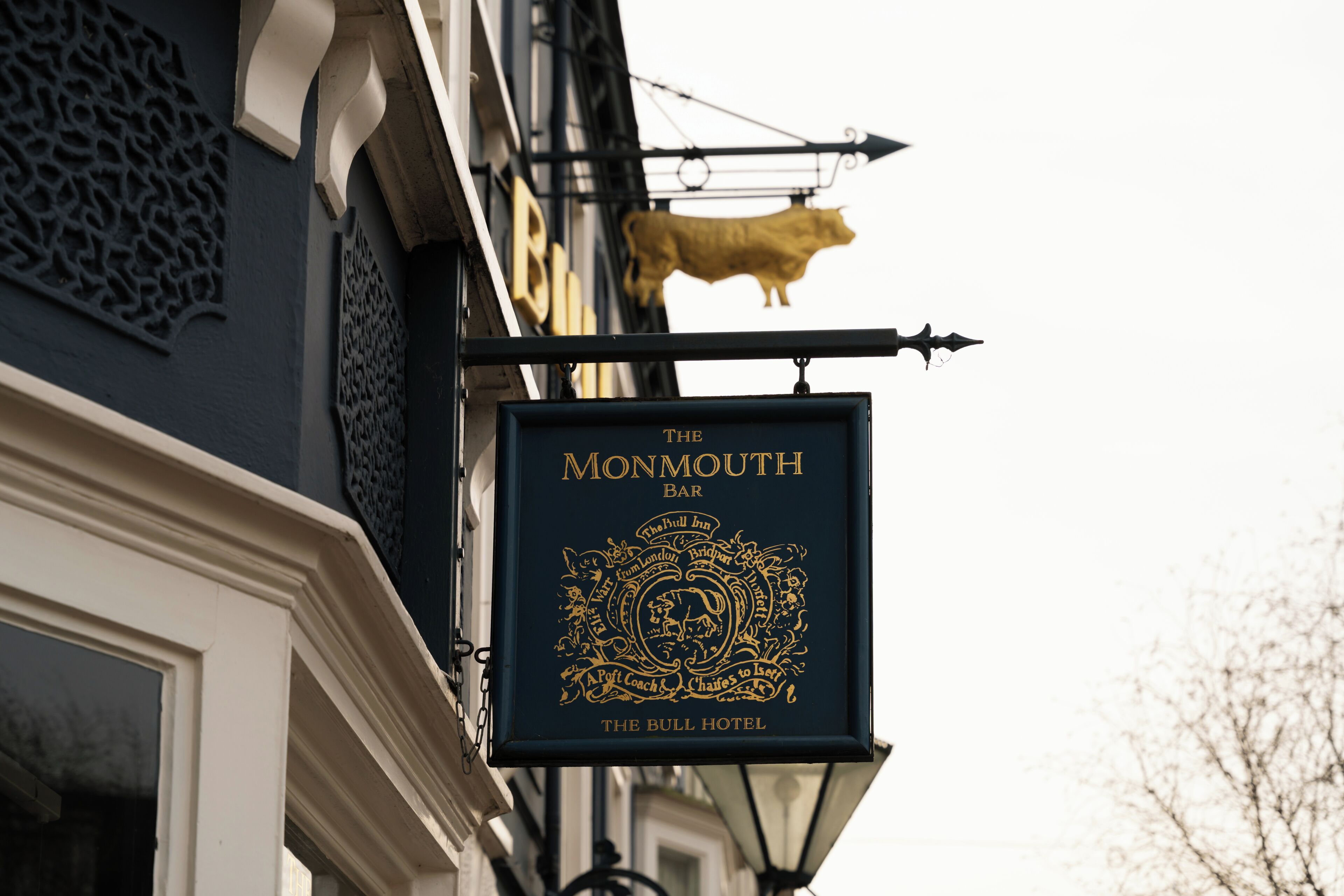 Une enseigne pour «The Monmouth Bar», avec un emblème doré et le texte «The Bull Hotel» en dessous.