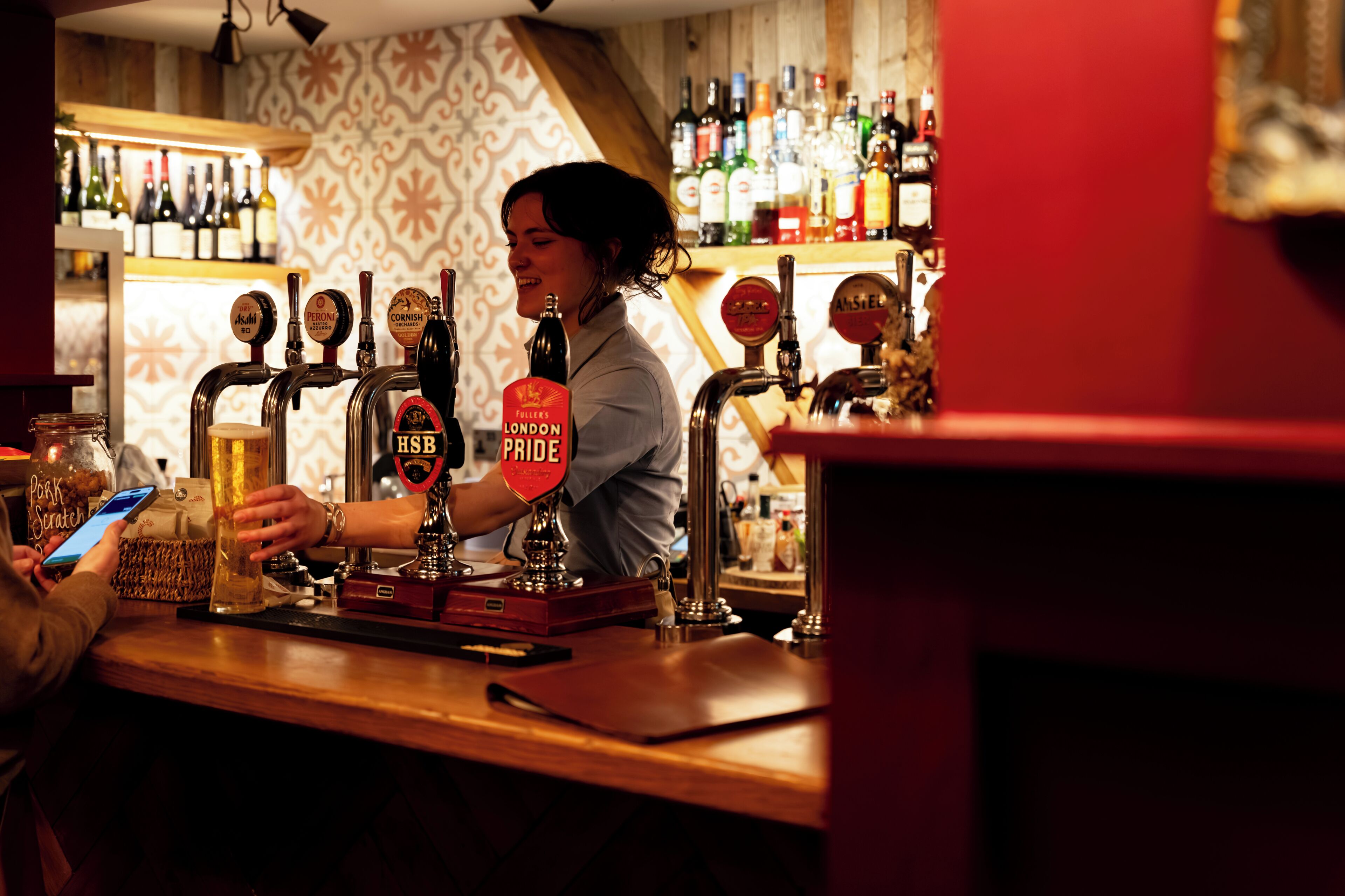 A bar with multiple beer taps, a counter, and a variety of bottles in the background.