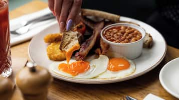 Une assiette de petit-déjeuner avec des œufs, du bacon, des haricots et des toasts.