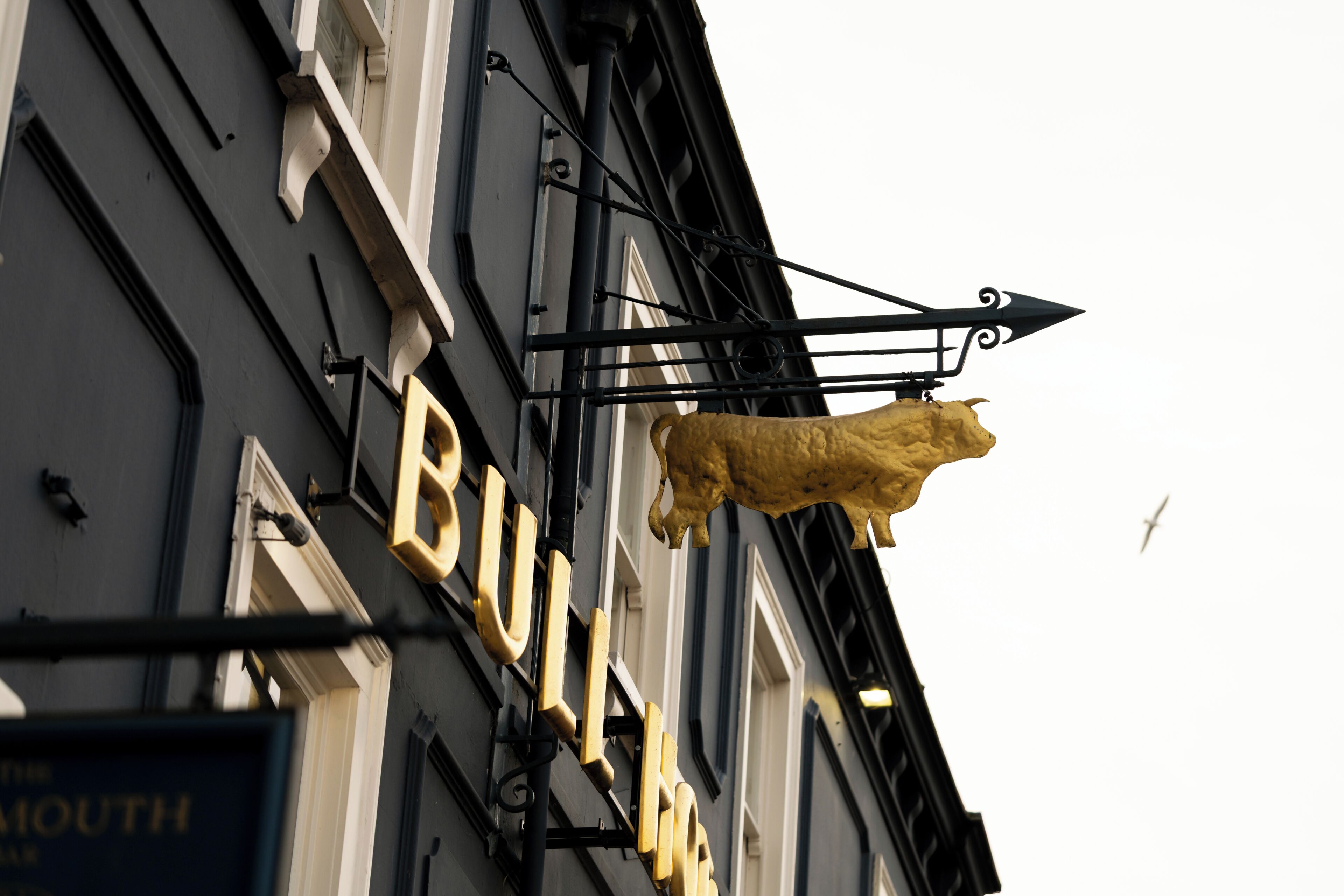 Un edificio con un cartello ben visibile che riporta 'BULLHEADS' e una statua dorata di leone.