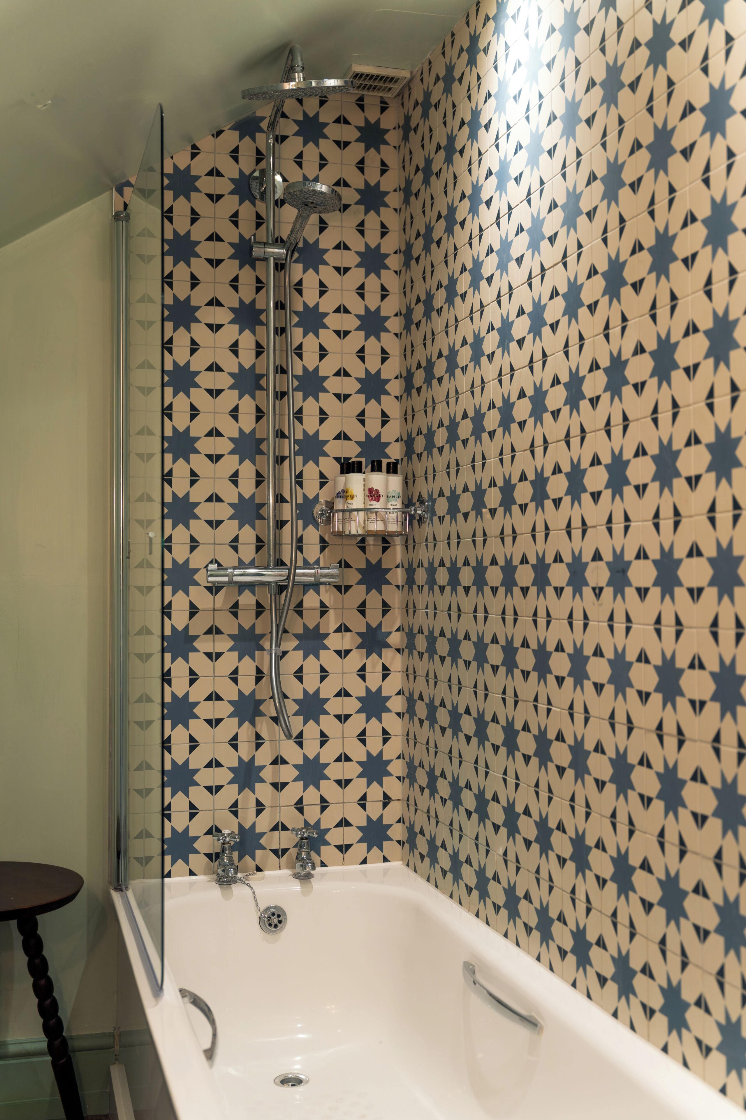 Ein Badezimmer mit Dusche, Badewanne und einer mit Sternenmuster gefliesten Wand.