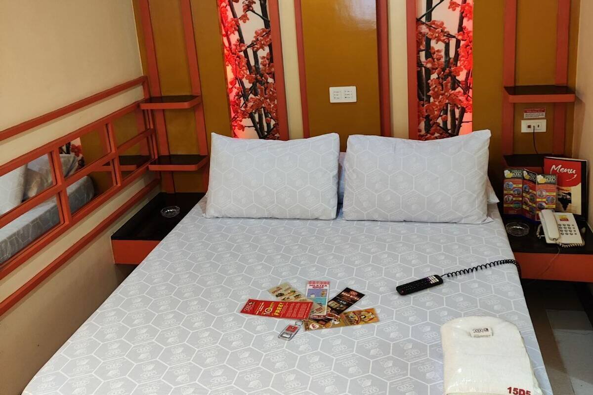 A hotel room with a bed, a nightstand, a telephone, and a wall with a floral design.