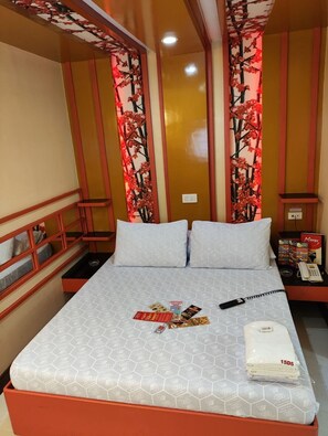 A hotel room with a bed, a nightstand, a telephone, and a wall with a floral design. - Hotel Sogo Recto (Manila)