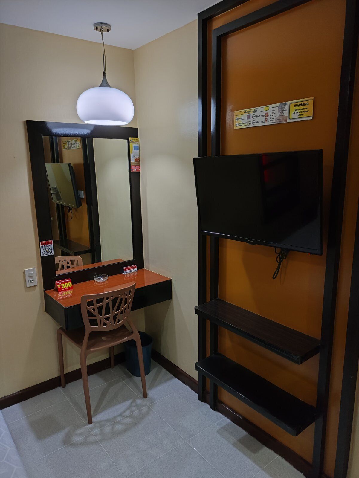 A small room with a desk, chair, and a TV mounted on the wall.