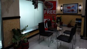 A restaurant interior with a promotional banner for half-fried chicken, potted plants, and a framed painting on the wall. - Hotel Sogo Recto (Manila)