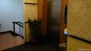 An elevator in a hallway with a sign indicating an exit. - Hotel Sogo Recto (Manila)