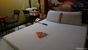 A hotel room with a bed, a desk, a chair, a phone, and a wall with a painting. - Hotel Sogo Recto (Manila)