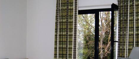 Una habitación de hotel con una cama, un escritorio, un televisor y una ventana con cortinas.