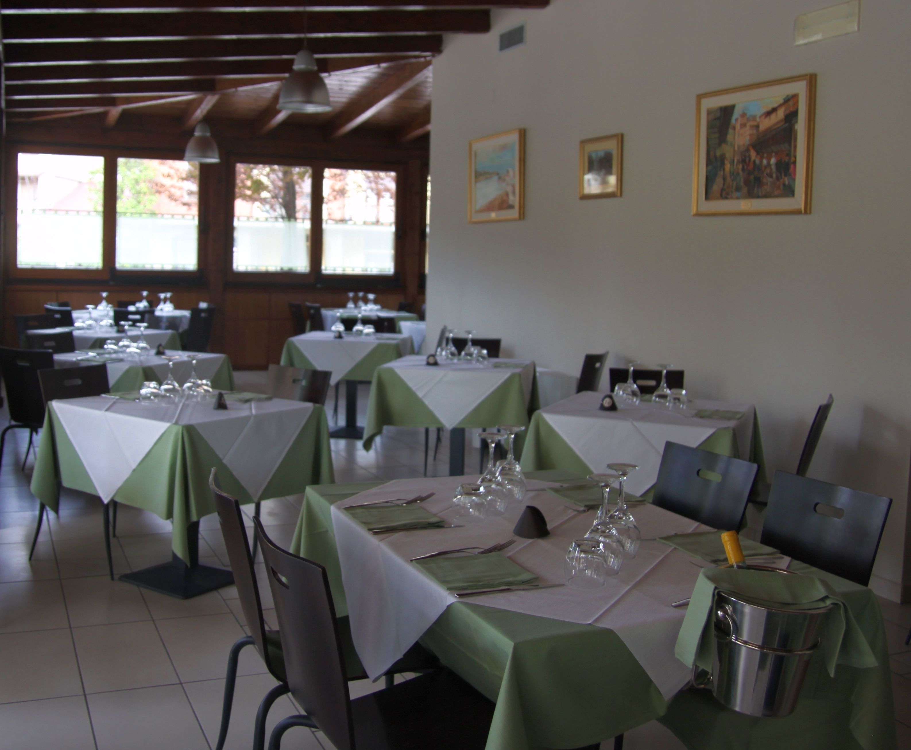 A restaurant with tables set for dining, featuring a green tablecloth and white table runners.