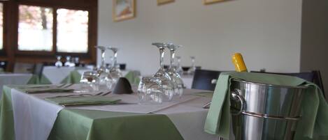 A dining table set with green tablecloths, clear glassware, and a champagne bottle in a metal bucket.