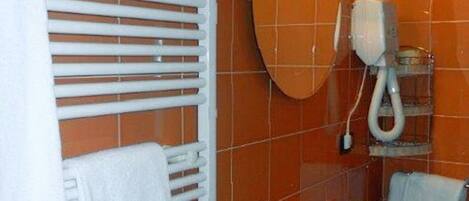 A bathroom with orange tiles, a white sink, a mirror, and a towel rack.