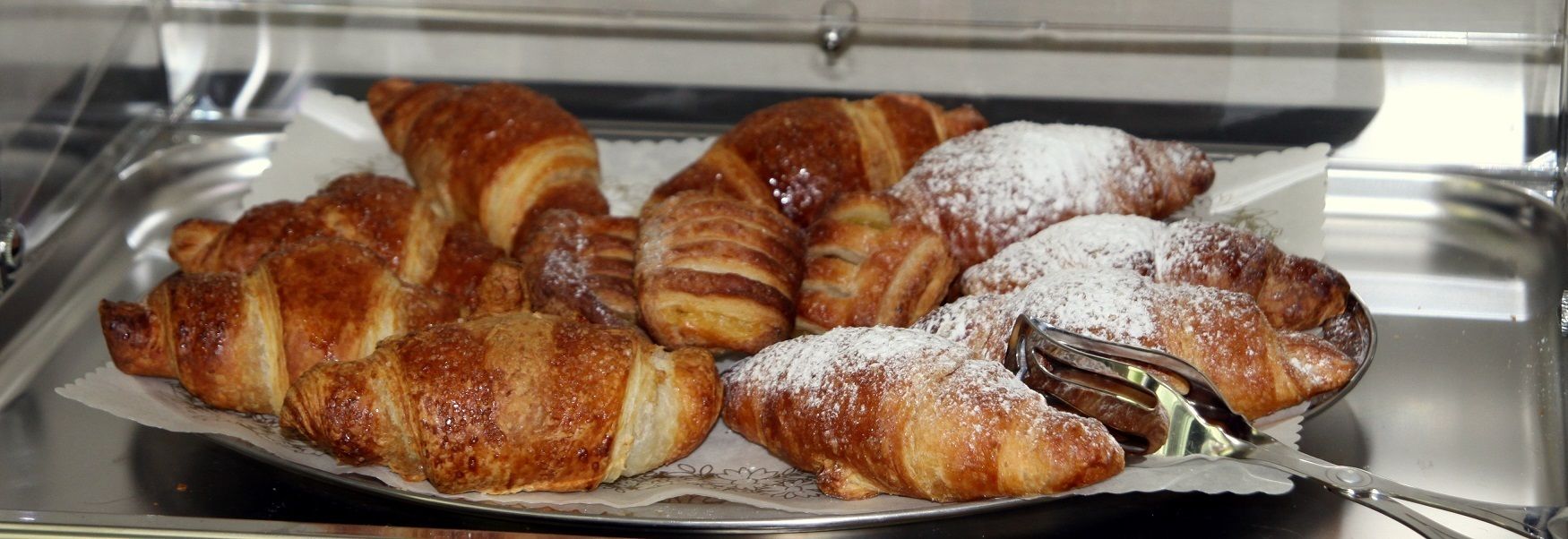 Un vassoio di dolci, tra cui croissant e croissant al cioccolato, spolverati di zucchero a velo.