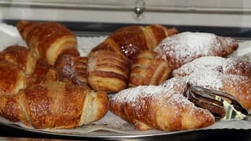 Un vassoio di dolci, tra cui croissant e croissant al cioccolato, spolverati di zucchero a velo.