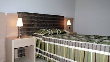 Una camera d'albergo ordinata con un letto, due comodini e due lampade.