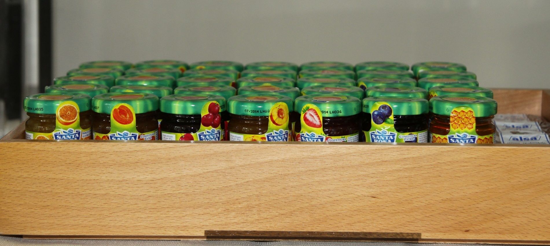 A wooden display case containing multiple jars of Santa Rosa jam, each with a green lid and a colorful label.