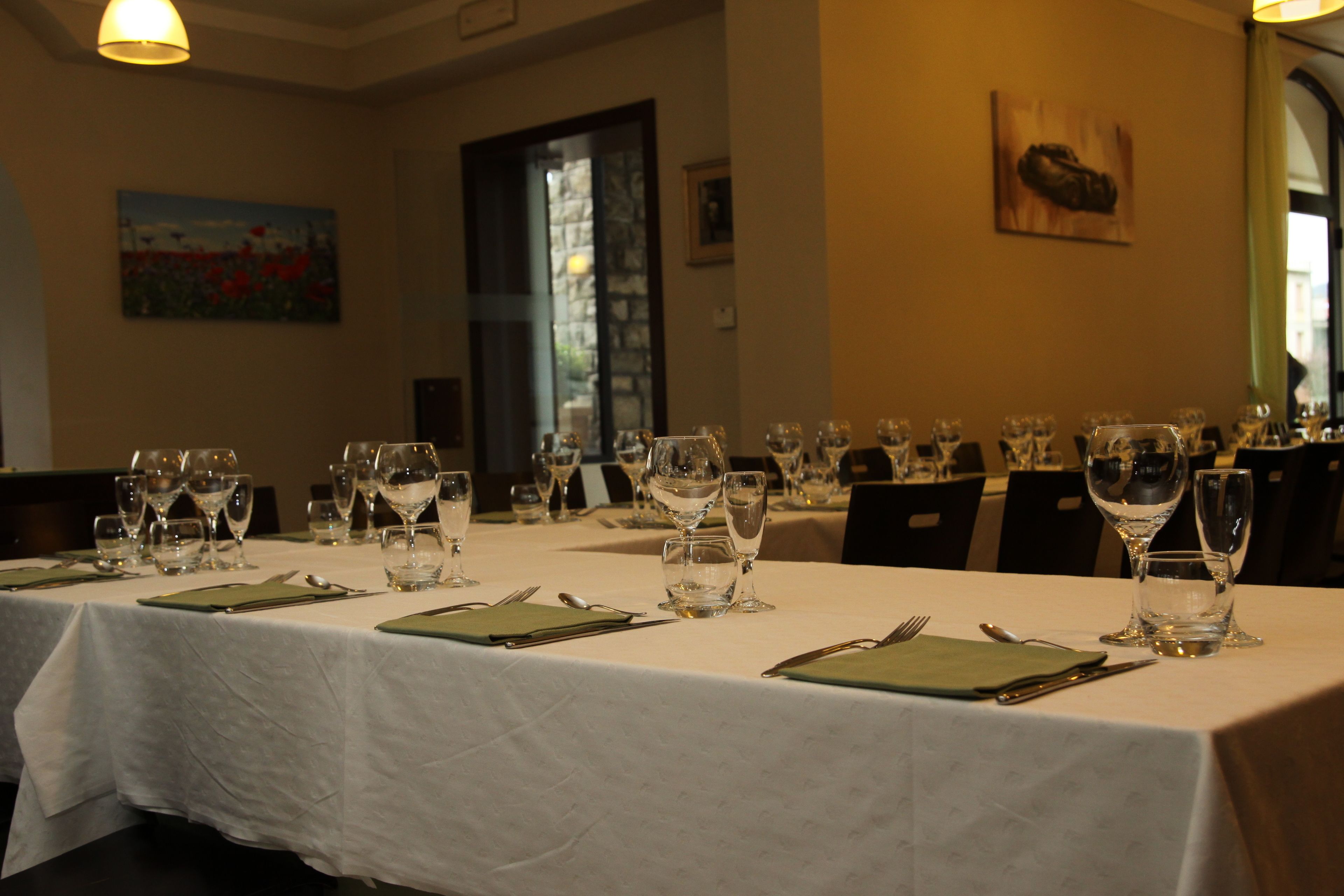 Una mesa de comedor dispuesta con varias copas de vino, cubiertos y servilletas verdes.