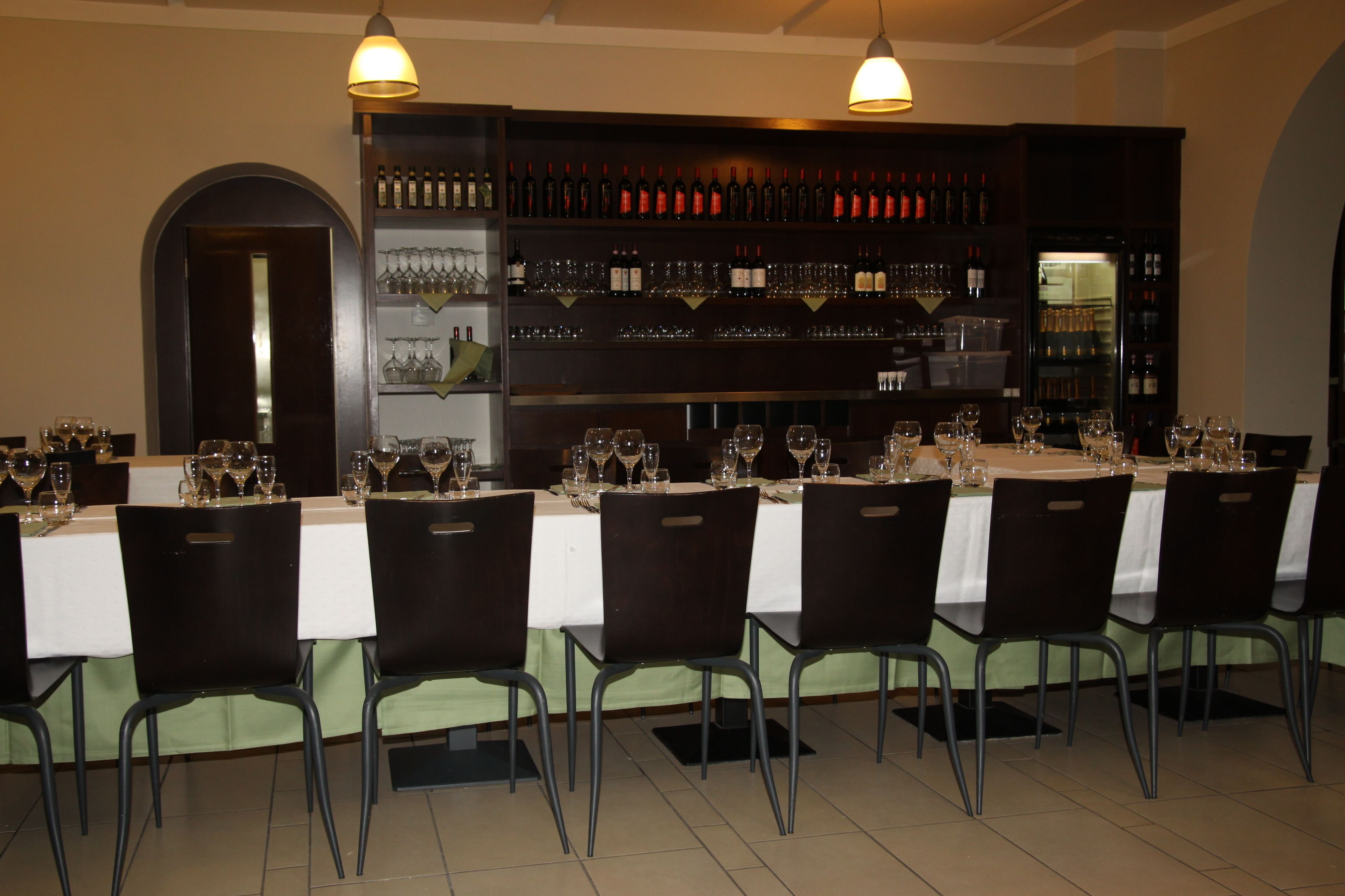 A restaurant with a long table set for a meal, surrounded by chairs.
