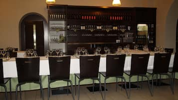 A restaurant with a long table set for a meal, surrounded by chairs.