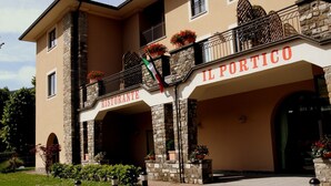 Un edificio con un letrero que dice "IL PORTICO RISTORANTE" y un balcón con plantas en macetas.