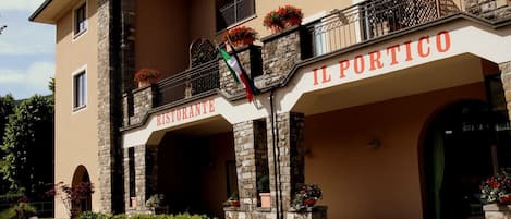 Un edificio con un letrero que dice "IL PORTICO RISTORANTE" y un balcón con plantas en macetas.