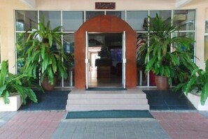 A building entrance with a wooden archway, potted plants, and a tiled entrance area. - Seri Malaysia Bagan Lalang (Sungai Pelek)