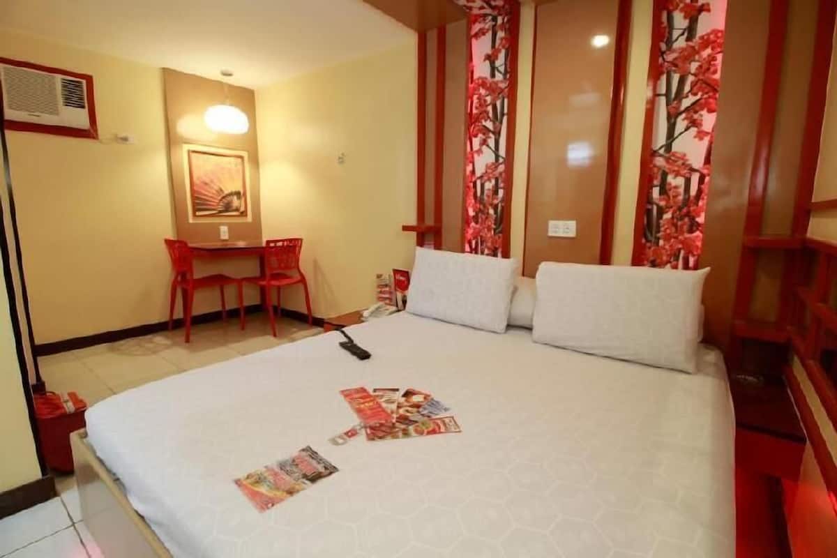 A hotel room with a bed, a desk, and a chair.
