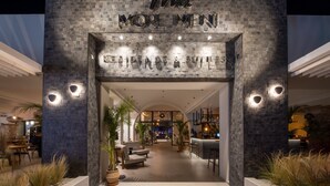 A modern hotel entrance with a stone facade and a sign reading "More Men." - Sentido More Meni Residence (Kos)