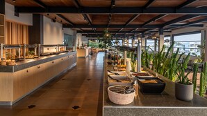 A spacious buffet area with a long counter, various food stations, and potted plants. - Sentido More Meni Residence (Kos)