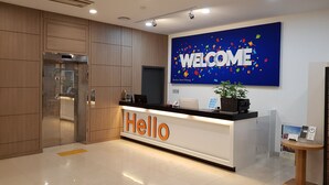 A hotel reception area with a 'WELCOME' sign, a reception desk, a plant, and a security camera. - Benikea Hotel Pohang (Pohang)