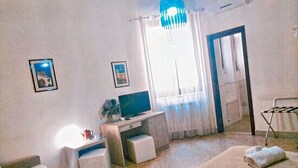 A room with a bed, a desk, a chair, a TV, and a window with curtains. - Il Quadrifoglio Room&Suite (Palermo)