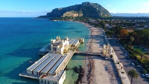 An aerial view of a coastal area with a beach, a marina with boats, and a mountain in the background. - Il Quadrifoglio Room&Suite (Palermo)