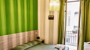 A hotel room with a bed, a nightstand, a hanging light fixture, and a view of the outside balcony. - Il Quadrifoglio Room&Suite (Palermo)