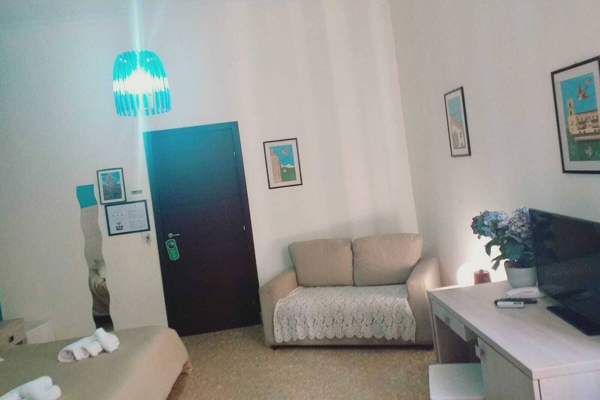 Ein Hotelzimmer mit Bett, Sofa, Schreibtisch und Fernseher.