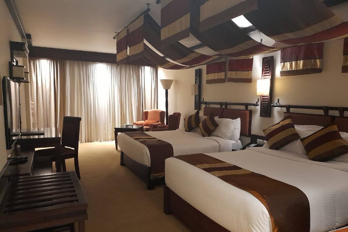 A hotel room with two beds, a desk, and a chair.
