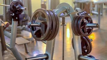 A gym with weightlifting equipment, including barbells and weight plates.
