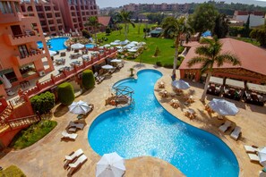 A resort with a large swimming pool, sun loungers, and umbrellas. - Africana Hotel & Spa (Al-'Amriyah)