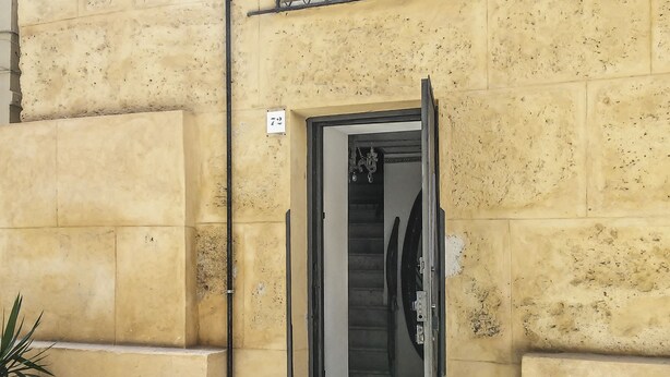 A yellow building with a metal gate and a number '72' sign. - Exclusive Dependance (Palermo)