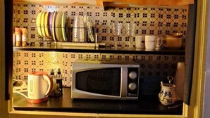 A compact kitchen with a microwave, kettle, and various kitchen utensils on the counter. - Exclusive Dependance (Palermo)