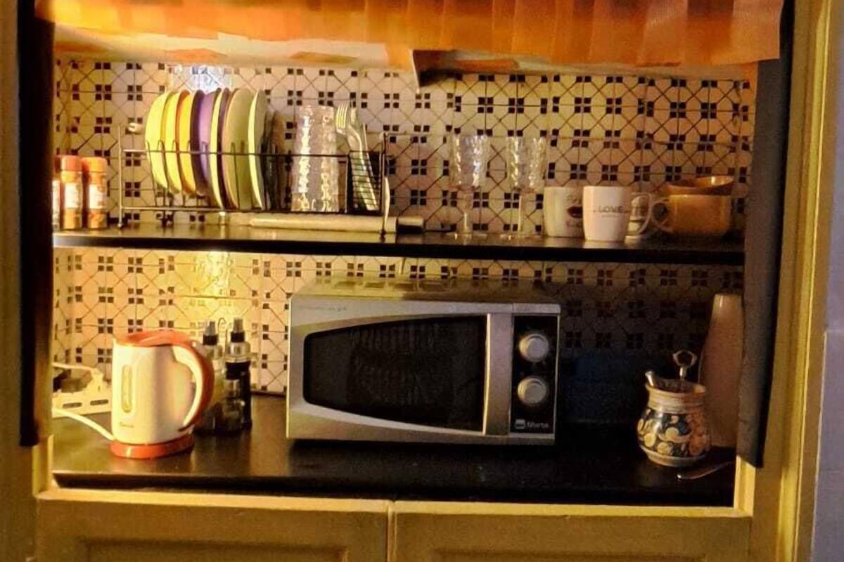 Una cocina compacta con microondas, hervidor y diferentes utensilios de cocina en la encimera.