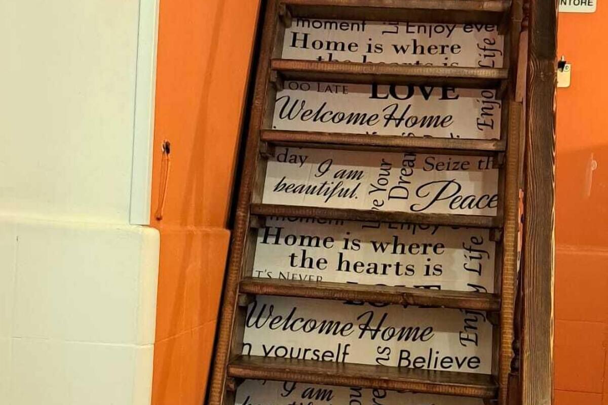 Una escalera de madera con varios peldaños, cada uno decorado con una señal que muestra frases motivacionales.