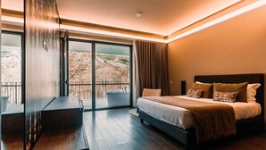 A modern bedroom with a large bed, a view of a mountainous landscape, and a sliding glass door leading to an outdoor area. - Aqua Village Health Resort & Spa (Oliveira do Hospital)