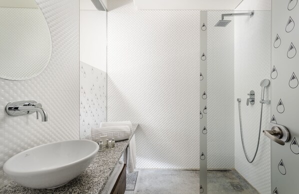 A modern bathroom with a large oval sink, a shower with a glass door, and a wall with water droplet patterns. - Aqua Village Health Resort & Spa (Oliveira do Hospital)