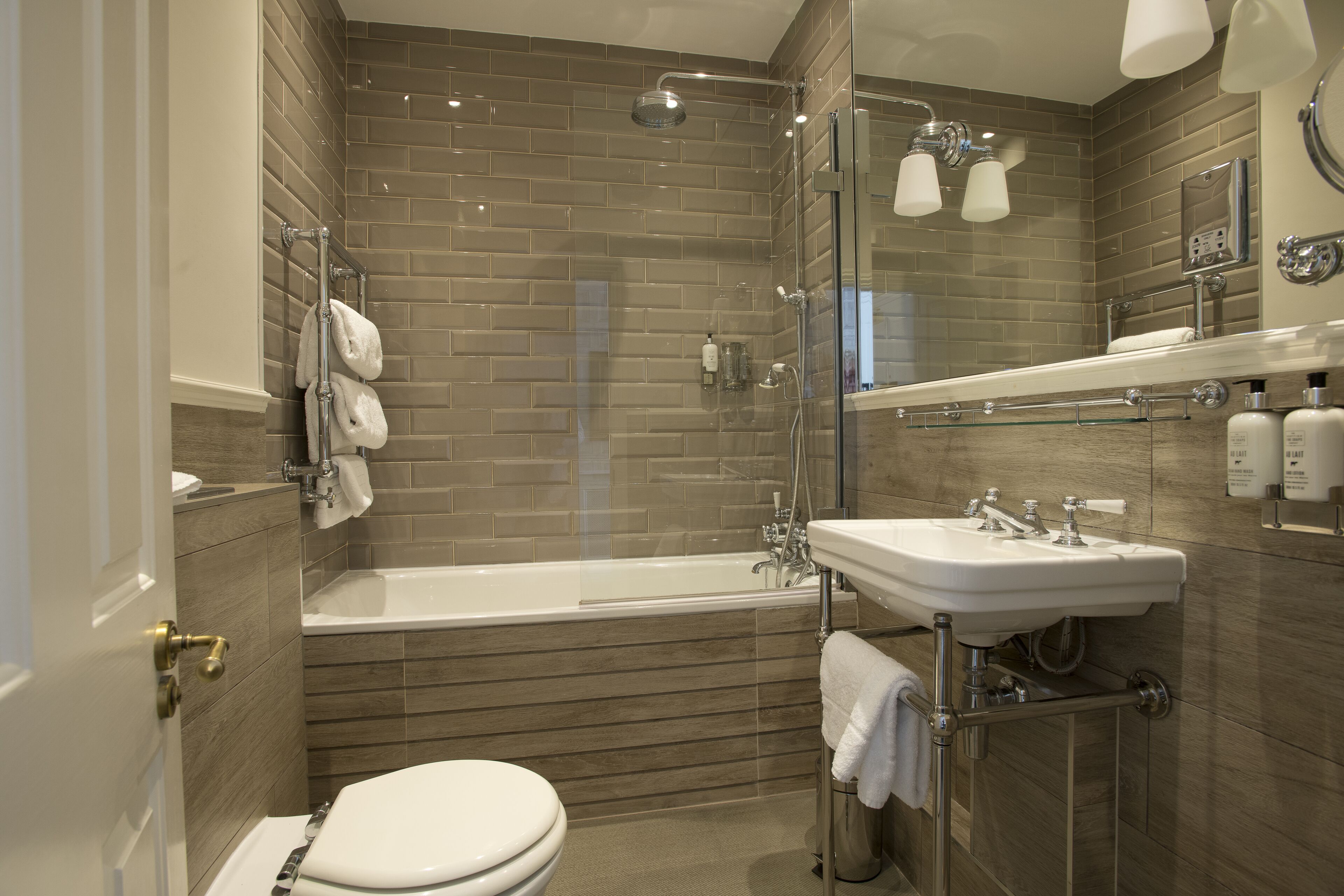 A modern bathroom with a bathtub, toilet, and glass-enclosed shower.