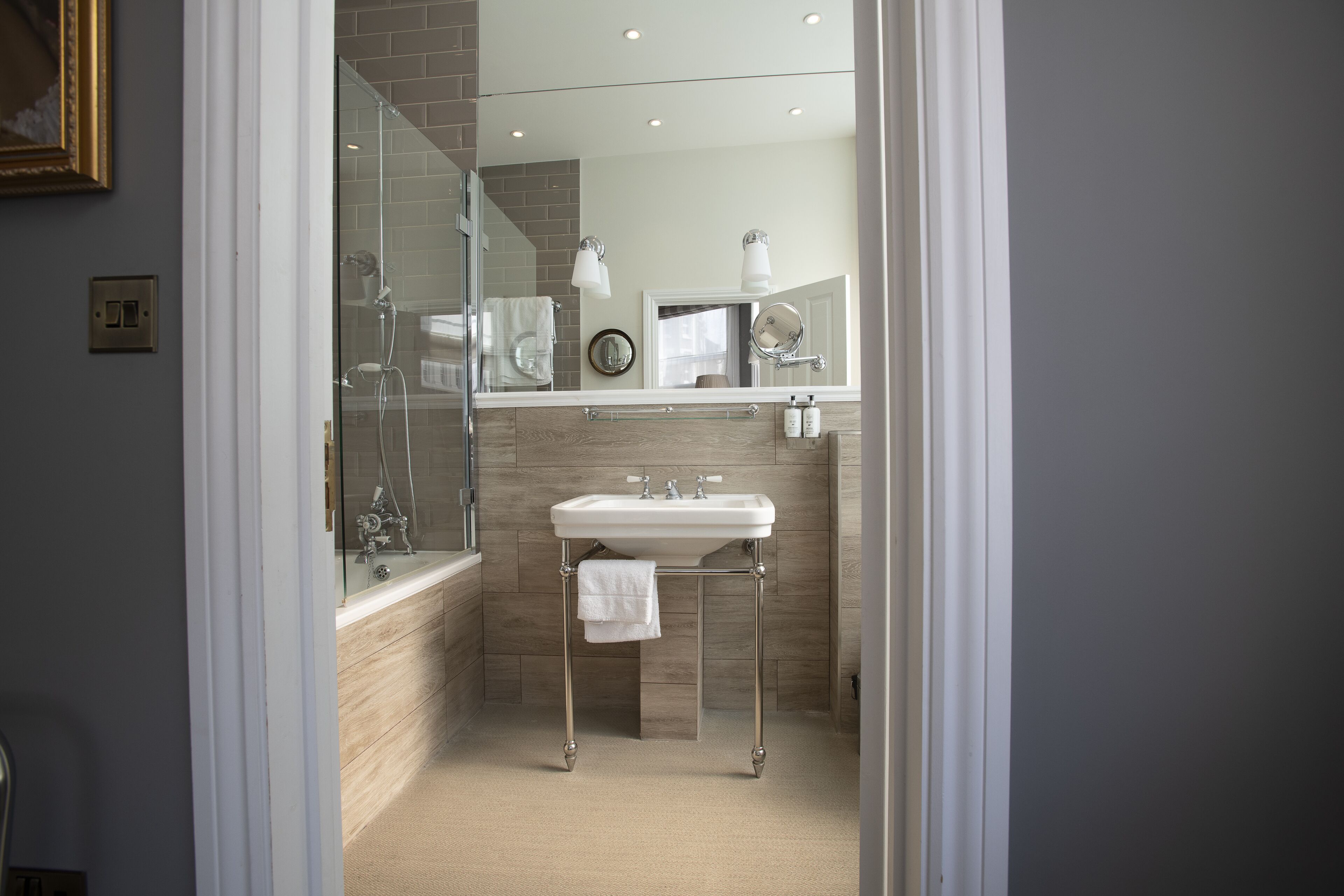 A modern bathroom with a glass-enclosed shower, a white sink, and a mirror above it.