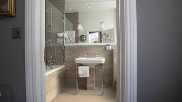 A modern bathroom with a glass-enclosed shower, a white sink, and a mirror above it.